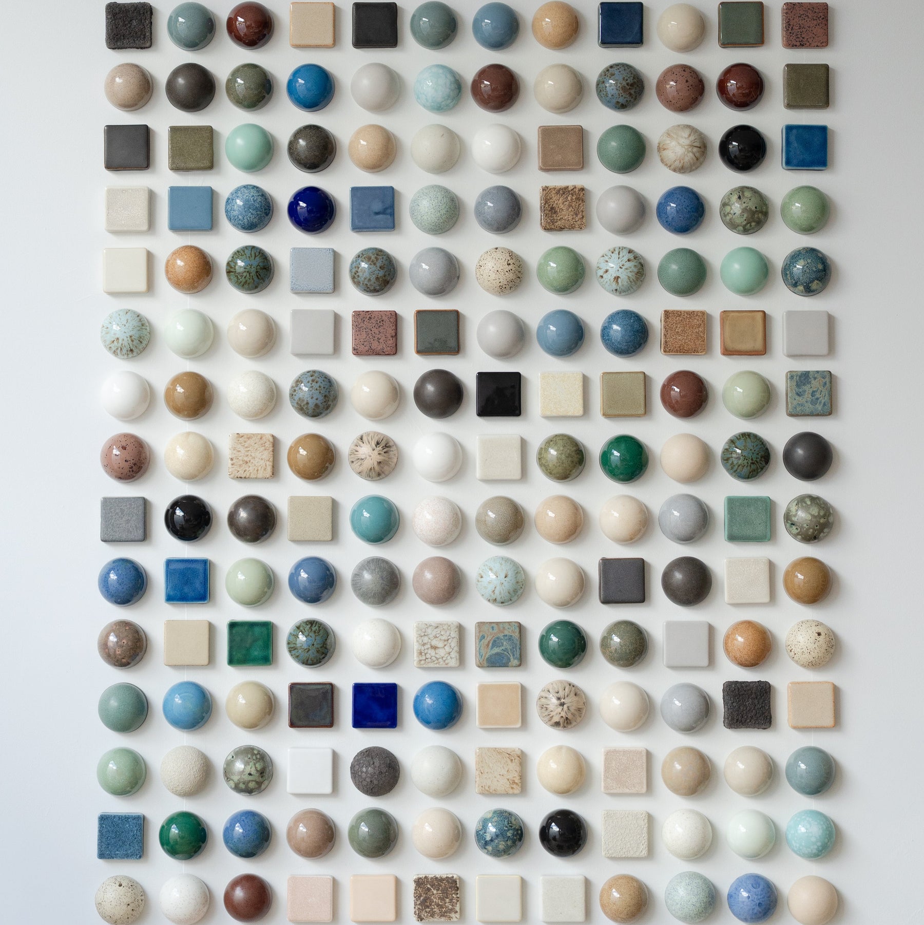 Sam Mayell ceramic domes and tiles in a grid of coloured glazes.